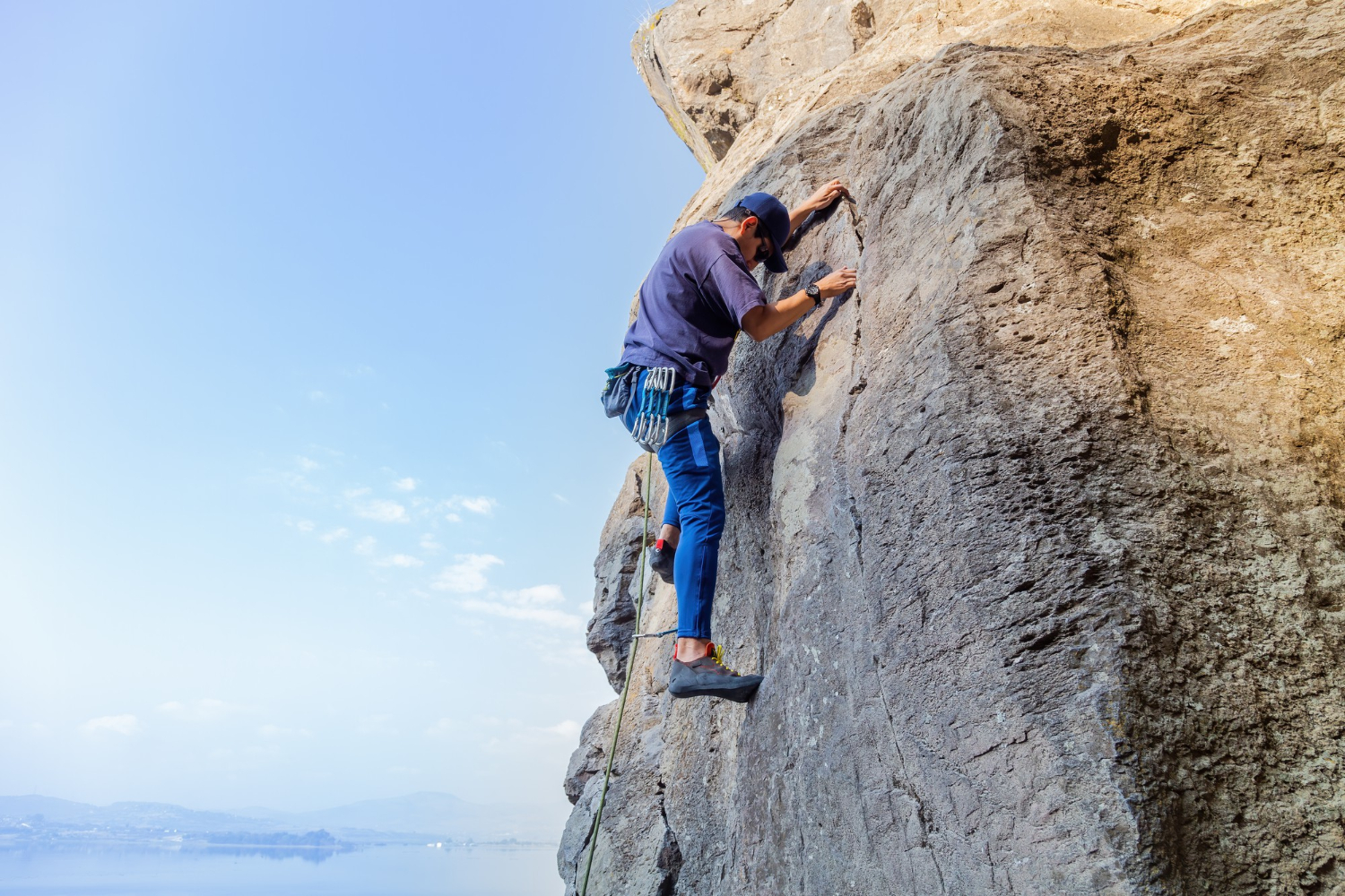 man with a rope engaged in the sports of rock climbing on the rock